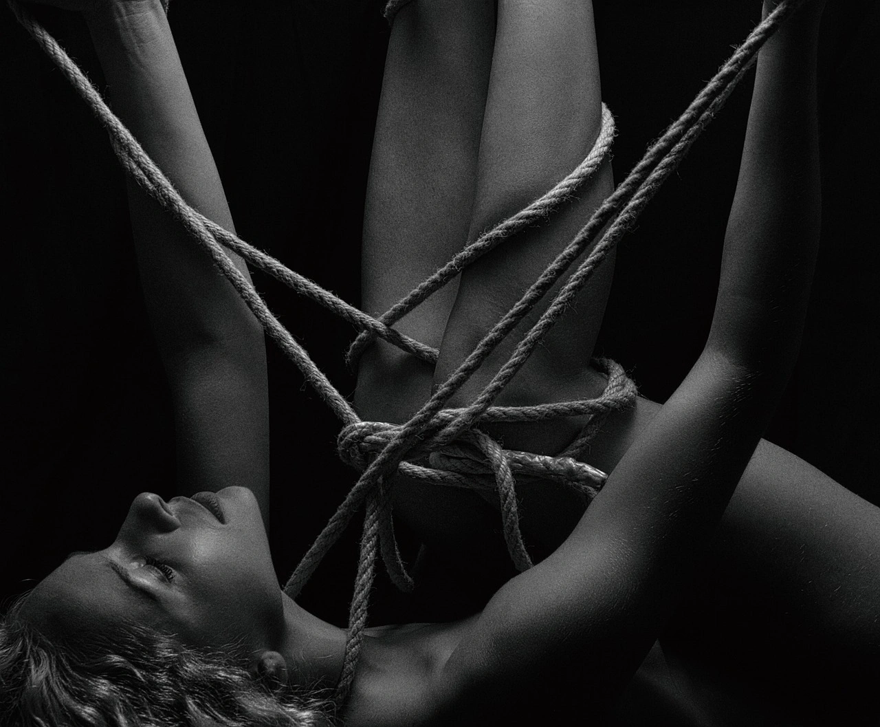 Nackte Frau, die mit Seilen zusammengebunden ist.